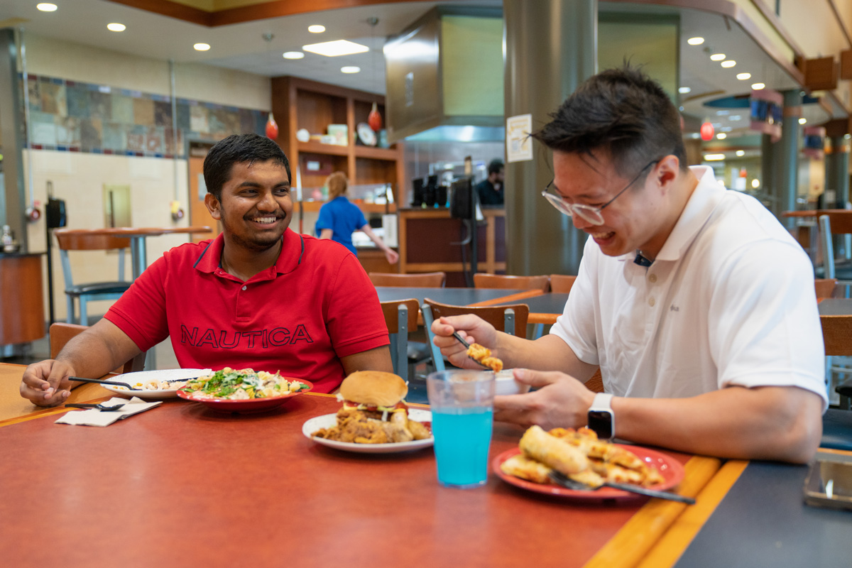 Two students laughing over a meal in Wiley Dining Court.